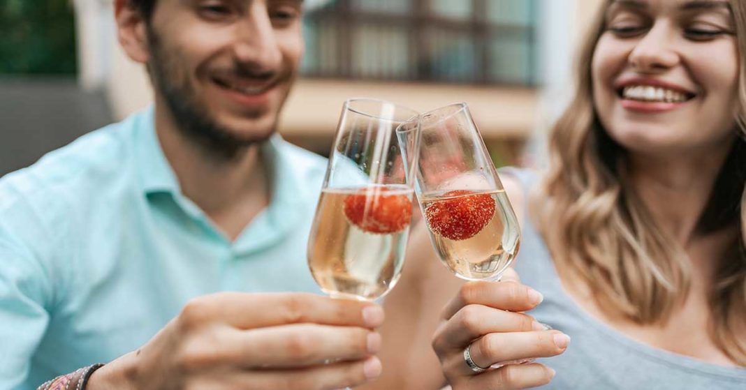 Happy couple drinking sparkling wine with strawberries